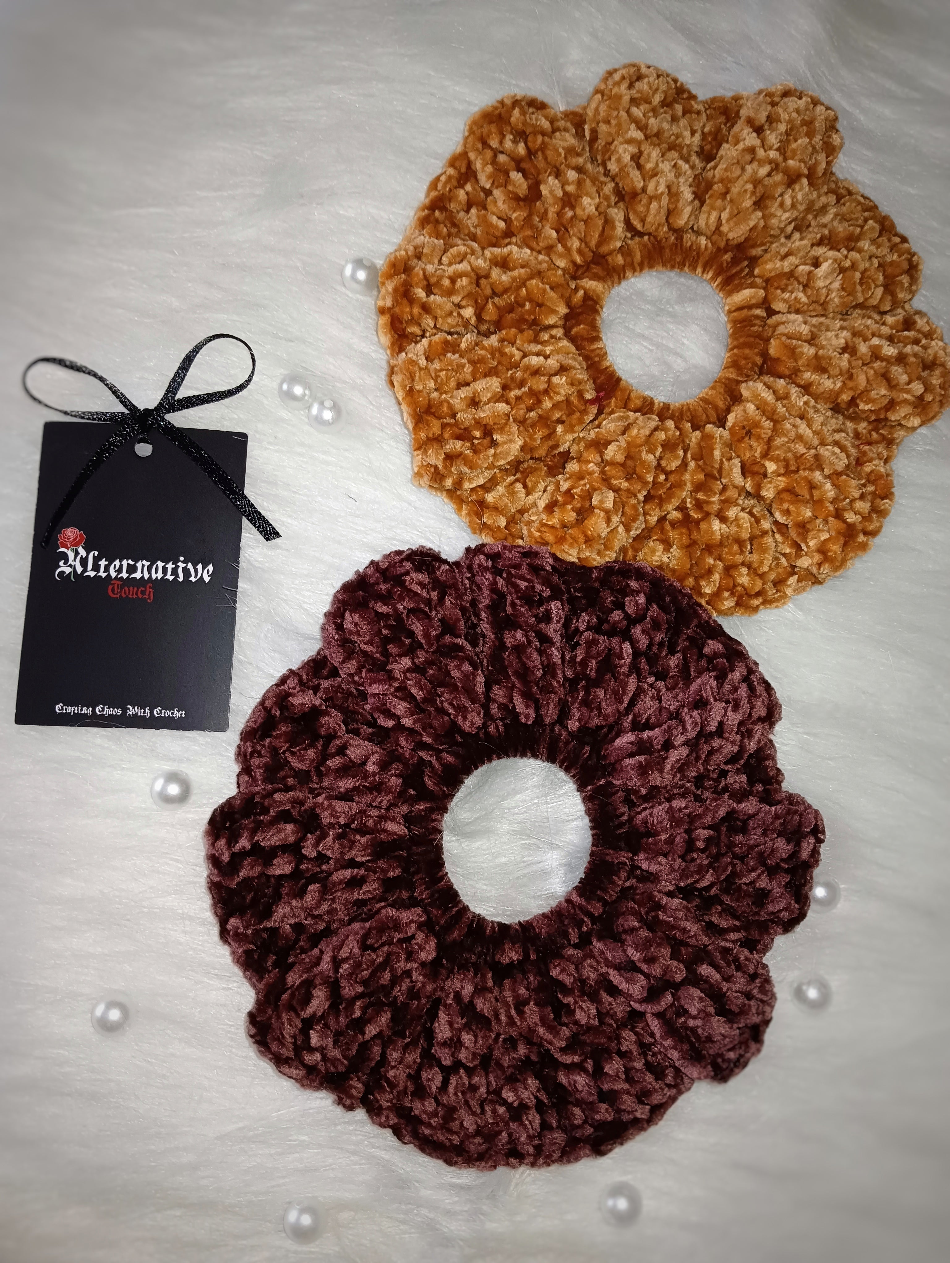 Two velvet scrunchies, one coffee brown and one chocolate brown, with a brand tag on a light background
