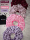Set of four velvet scrunchies in shades cherry pink, dusty pink, flamingo pink and lavender on a light background