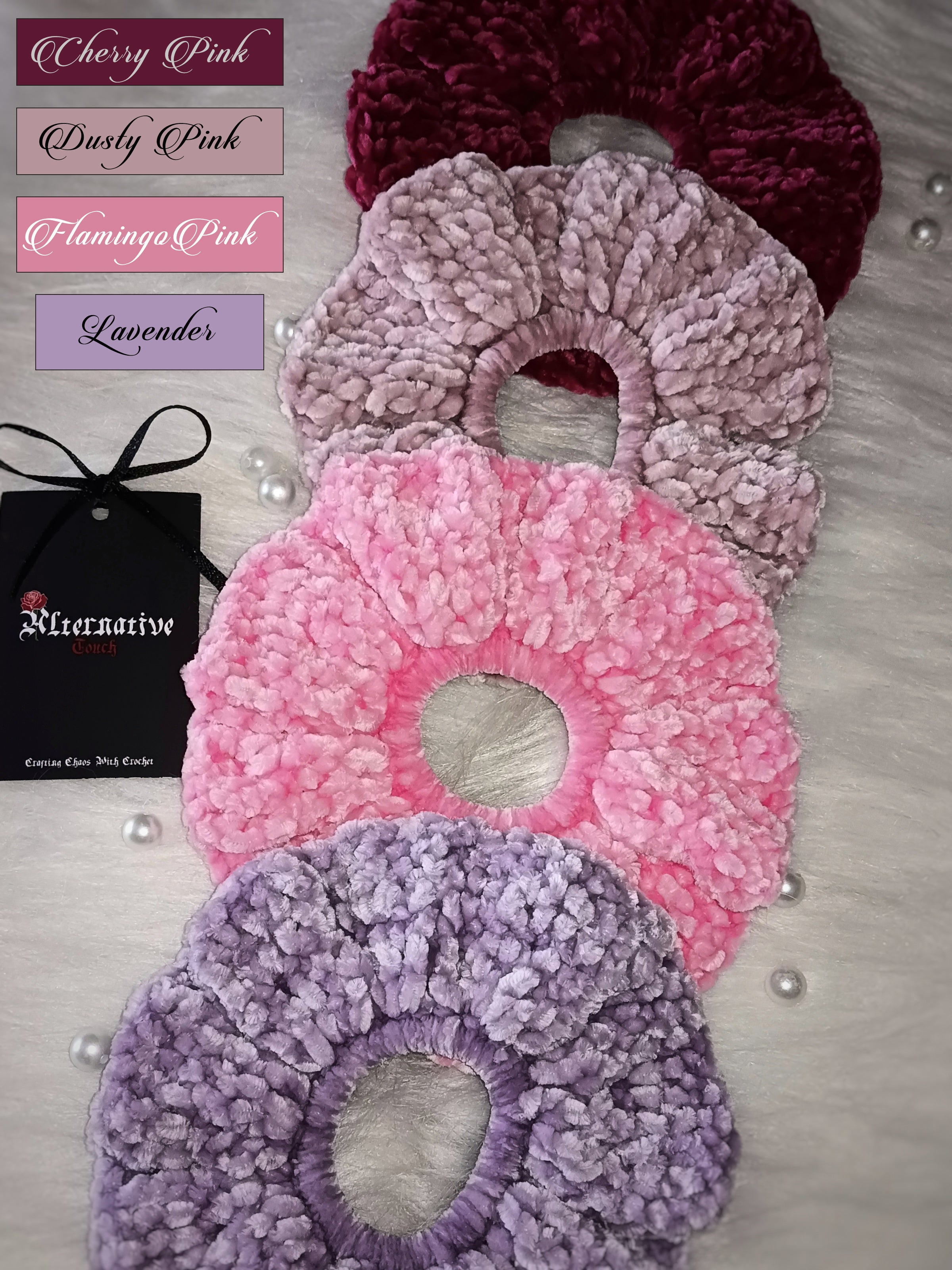 Set of four velvet scrunchies in shades cherry pink, dusty pink, flamingo pink and lavender on a light background