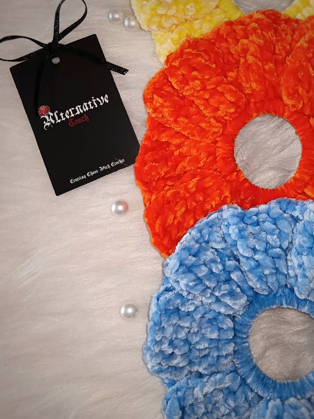 Colorful scrunchies on a textured surface with a brand tag on the side.