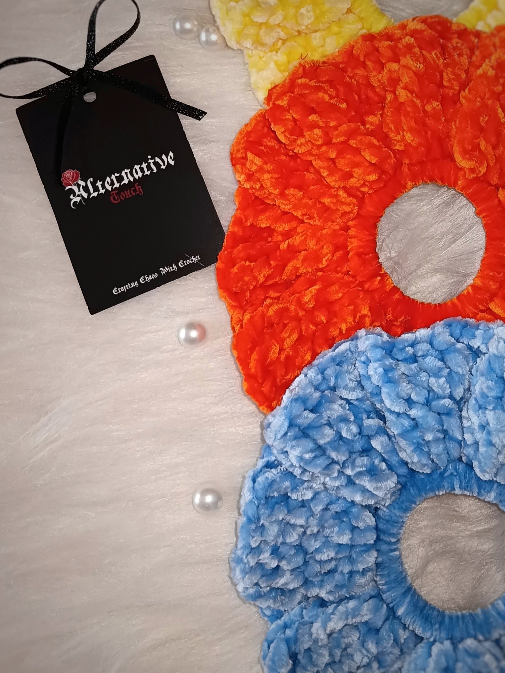 Colorful scrunchies on a textured surface with a brand tag on the side.