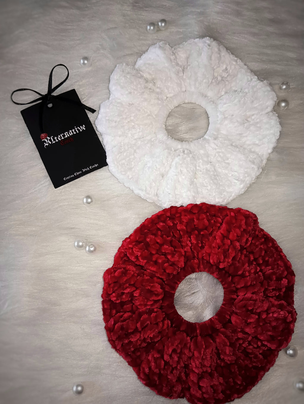 White and red scrunchies with a tag labeled 'Alternative Touch' on a white background.